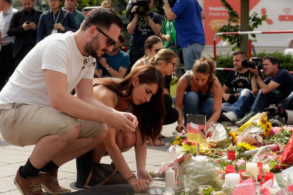 People lay flowers and candles outside the OEZ shopping centre.  Photo: Johannes Simon