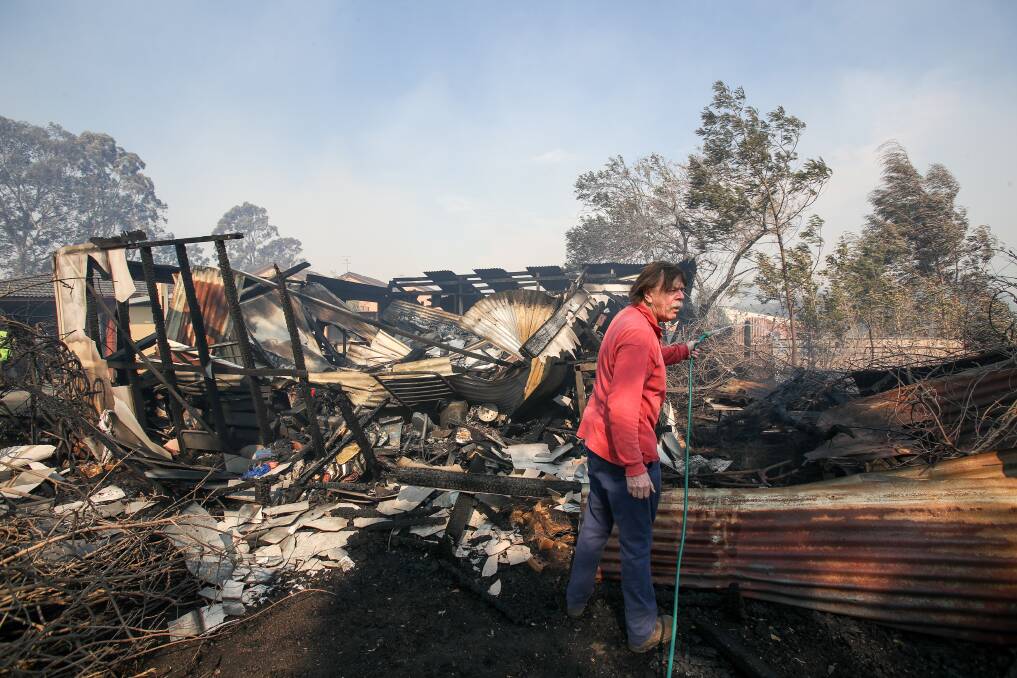 A resident hoses down a shed destroyed by the fire at Bomaderry.  Photo: Adam McLean