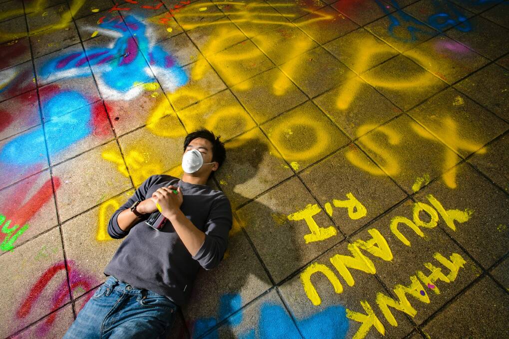 Third-year ANU Arts/Law student Bolwen Fu was one of dozens of students who seized an opportunity to spraypaint messages on the university's Union Court before the area is closed off for demolition.  Photo: Sitthixay Ditthavong