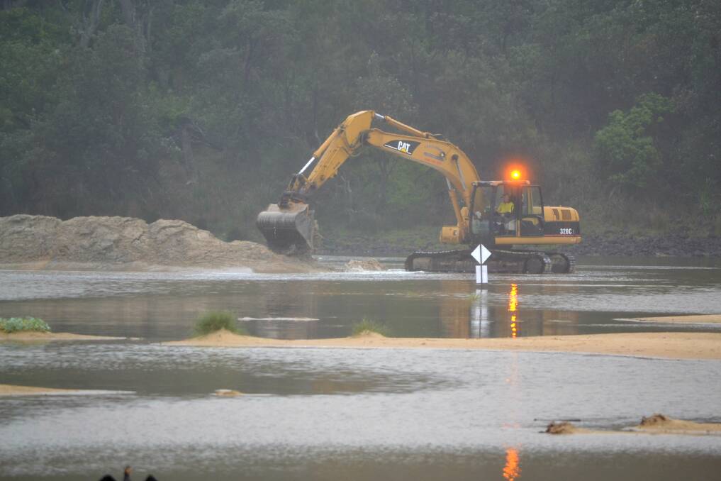 An excavator begins to dig out a channel in the sandbar blocking off Lake Conjola from the ocean on December18, 2018. Photo: Sam Strong