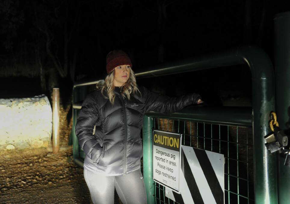 Michaela Vodvarka at Mount Jerrabomberra on Monday night near a sign warning of a dangerous pig. Photo: Melissa Adams