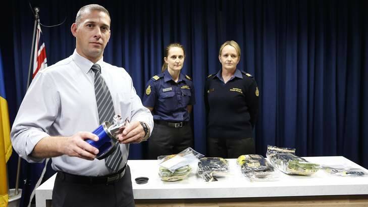 ACT Policing drug and organised crime team detective sergeant Shane Scott shows how drugs were concealed in a mug with officers from the Australian Customs and Border Protection Service. Photo: Jeffrey Chan