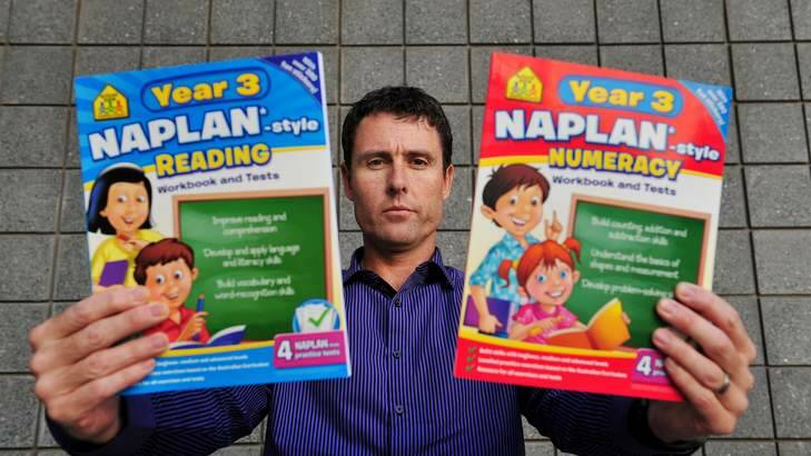 Australian Education Union ACT branch president Glenn Fowler with the popular workbooks. He said parents need to understand the assessments are "not the HSC for seven-year-olds''. Photo: Colleen Petch