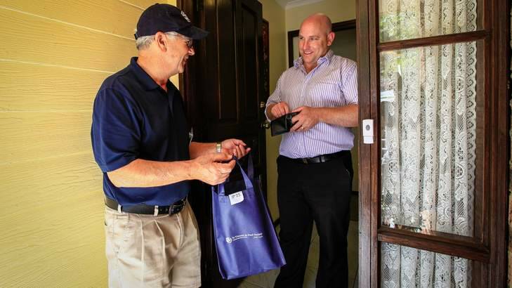 Sam Palma, 72 of Calwell, has been a St Vincent de Paul doorknock volunteer for 27 years. Mark Thompson (right) donates to the appeal. Photo: Katherine Griffiths