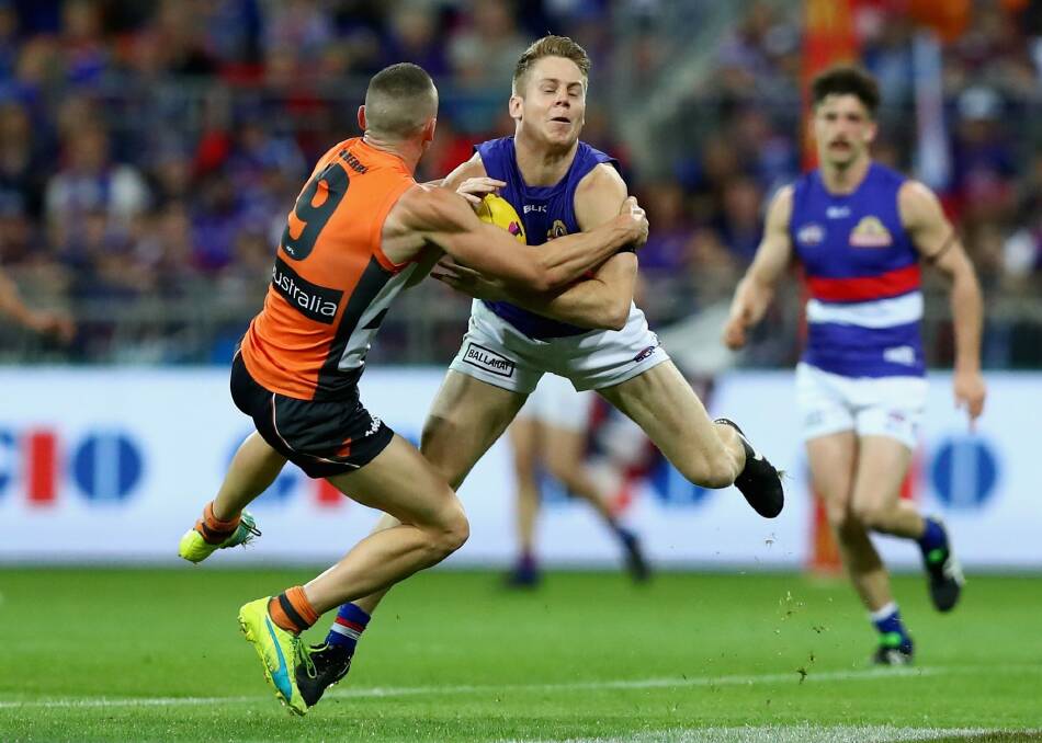 Giving it everything: Lachie Hunter of the Bulldogs is tackled by Tom Scully of the Giants. Photo: Getty Images