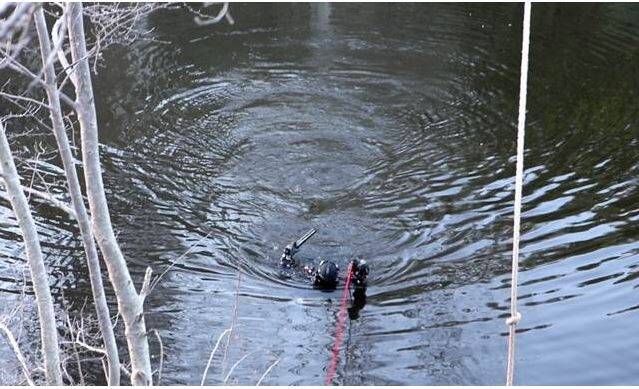 A police diver emerges from the Queanbeyan River holding a gun. Photo: Roberts, Troy