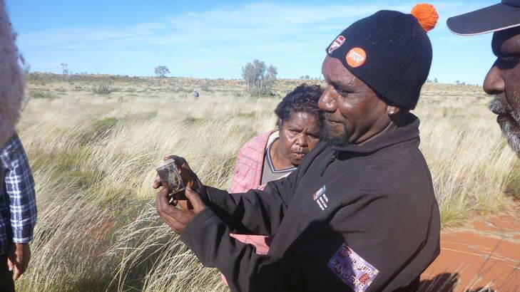 Robbie Wongawol and Martu land managers from Western Australia's central desert region looking at an insect that may be food for small marsupials. Photo: Supplied