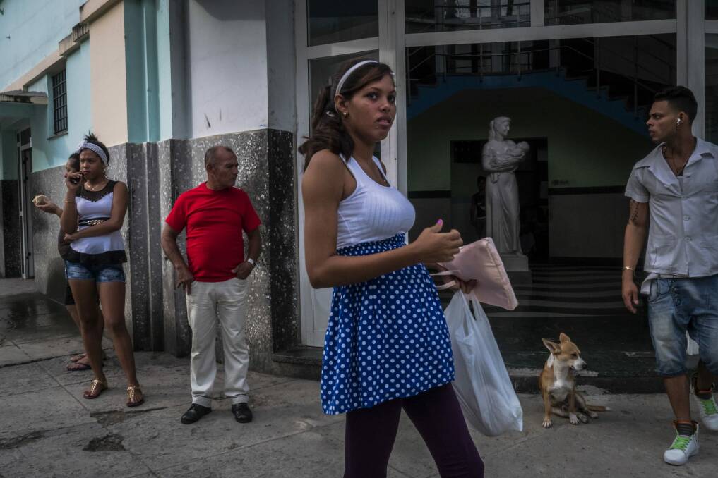 A pregnant woman waits for family members outside a hospital in Havana. Many young Cubans are avoiding having children. Photo: New York Times