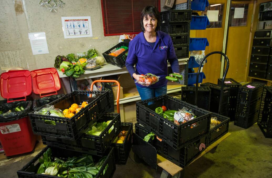 HandUp manager Sandra MacDonald sorts produce to go on to shelves.
  Photo: Elesa Kurtz