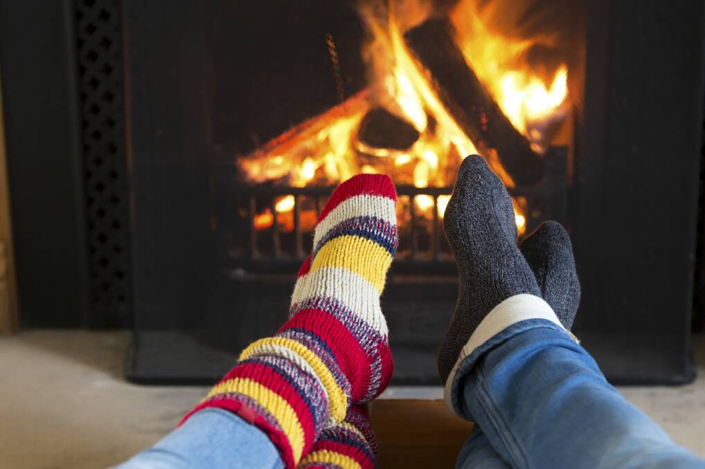 Think of creative ways to keep warm: wear woolly socks and snuggle in front of the fire. Photo: Supplied