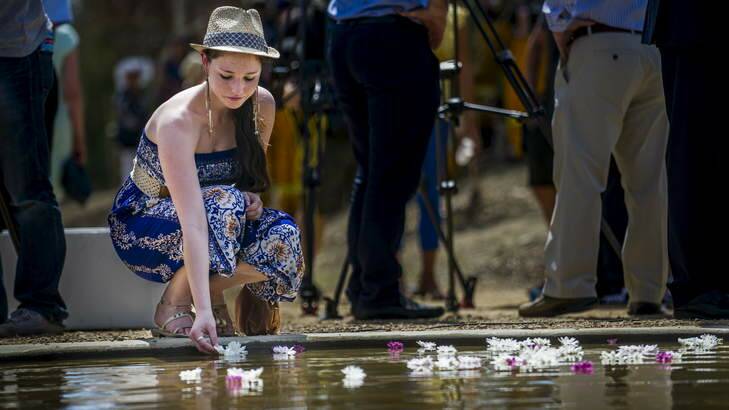 Bronte Forrester, 17, who lost her home in the 2003 fires leaves a flower in the pool at the bushfire memorial on Friday. Photo: Rohan Thomson