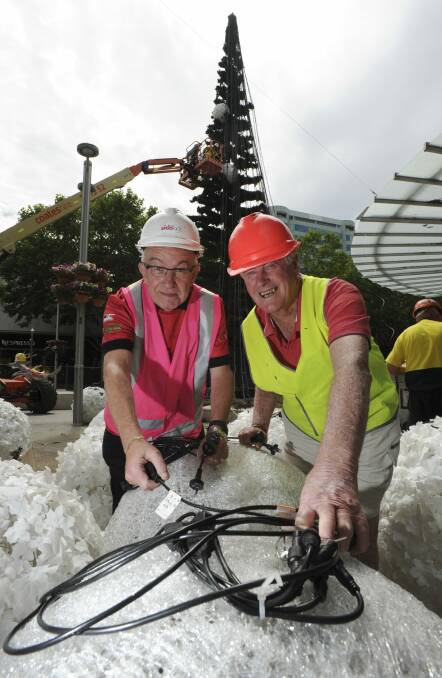 Volunteers Geoff Harding of Mawson, left and Rex Hall of Scullin, are helping to bring the potentially world-record-breaking Christmas tree lights to life in City Walk.
 Photo: Graham Tidy