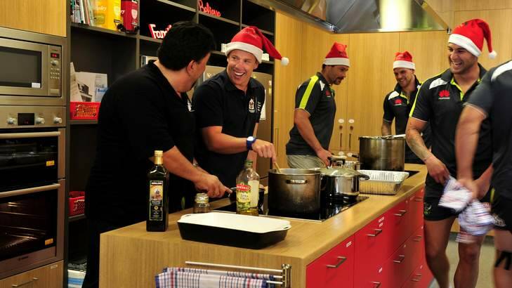 Raiders player Sam Williams is guided by La Scala owner, Gabriele Saccardo, as they prepare meals for families at the Ronald McDonald House, Canberra Hospital. Photo: Melissa Adams