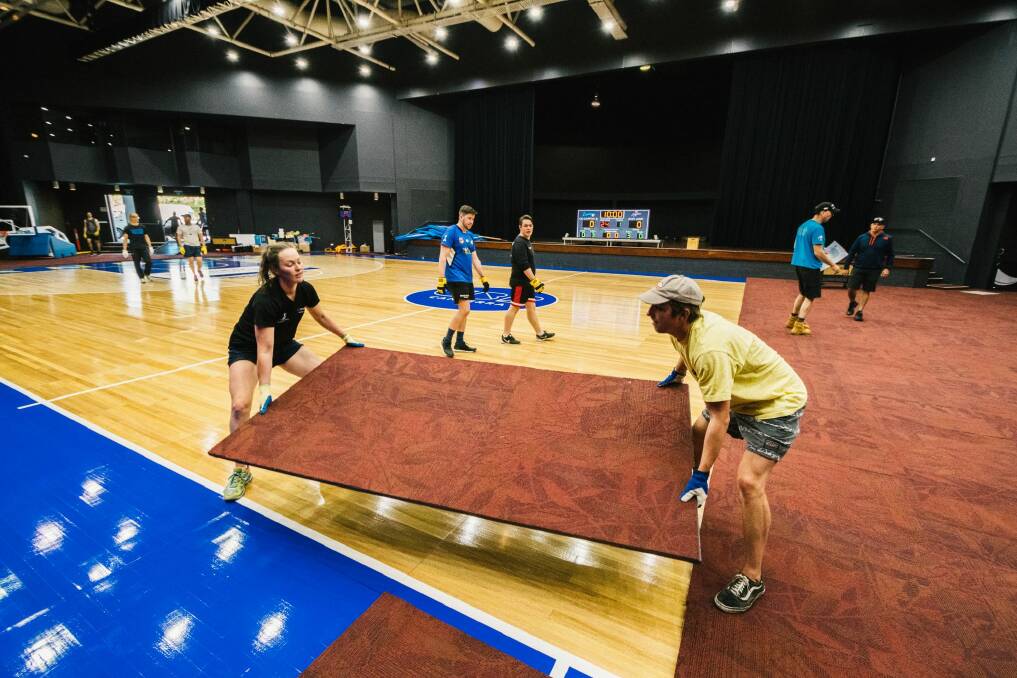 Workers remove panels to reveal the basketball court at the National Convention Centre. Photo: Rohan Thomson