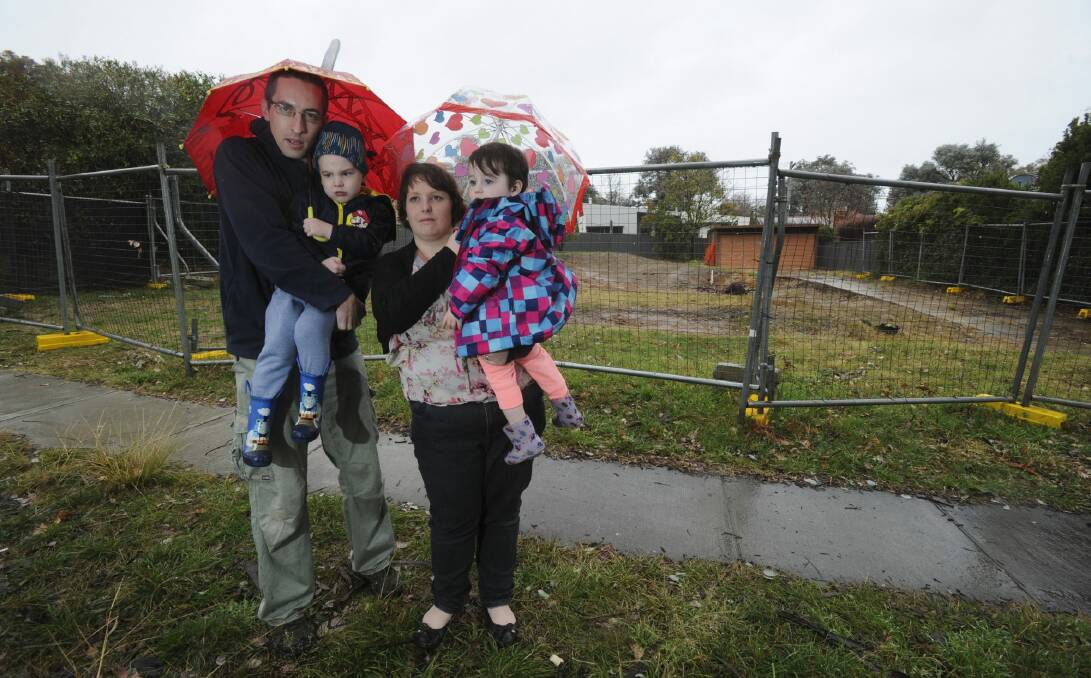 Chris and Christina Pilkington, with their children Theodore, 4, and Isabelle, 2, in front of the Mr Fluffy demolition site they have bought back and plan to rebuild. Photo: Graham Tidy