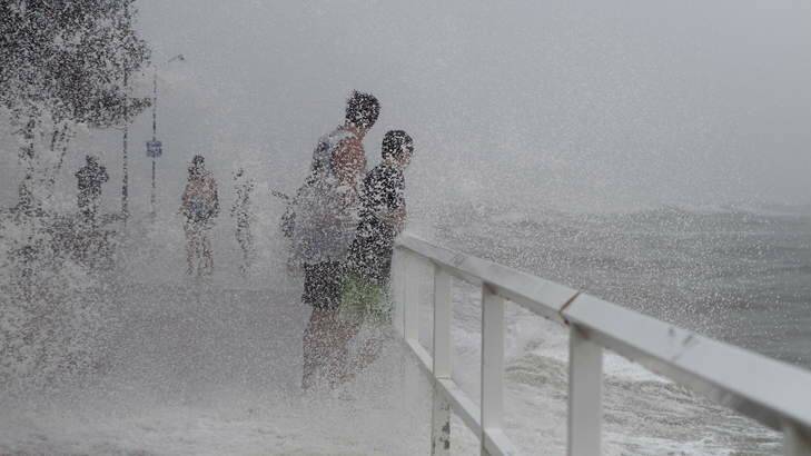 Locals at Shorncliffe Pier near Brisbane check out the storm surge during the cyclonic conditions affecting the coast of Queensland and northern New South Wales on Sunday. Photo: Michelle Smith