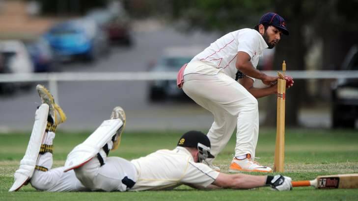 Eastlake player Kuunal Lall whips the bails off as Ginninderra batsman Nick Owen slides safely past the crease. Photo: Graham Tidy