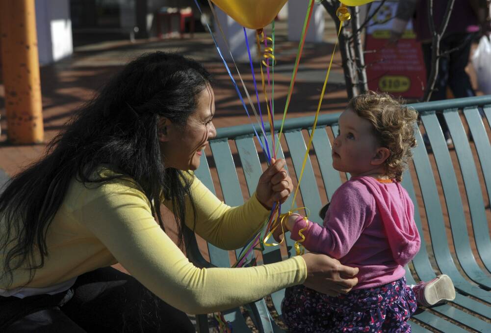 Elizabeth Kikkert gives a balloon to Ainsley Dawes, 23 months, of Evatt. Photo: Graham Tidy