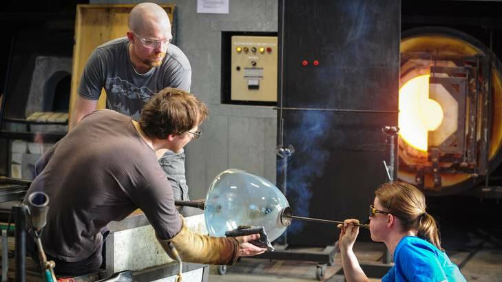 Glass artists Andrea Fiebig, right, uses a soffieta to blow air and expand the glass with Andy Baldwin and Brian Corr, rear. Photo: Katheirne Griffiths