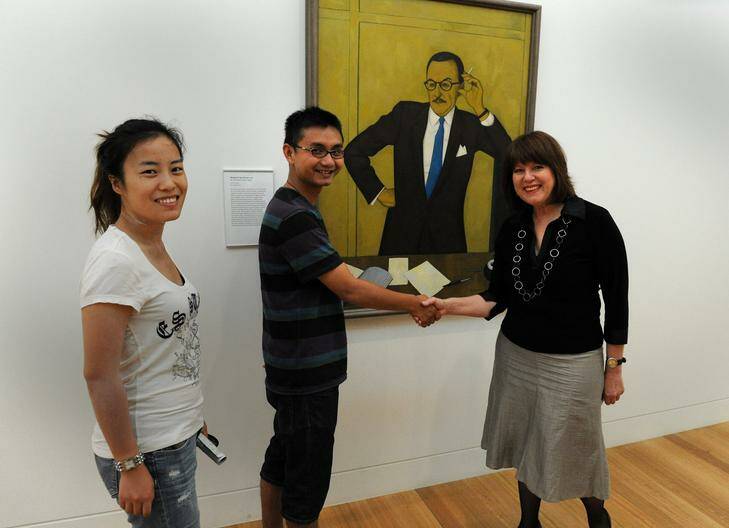 Gallery director Louise Doyle welcomes the two-millionth visitors to the National Portrait Gallery Edmund  Jiang and Vicki Ma, from Perth, with the newly hung portrait of  Australian Galleries founder  Tam (Thomas)  Purves .  Story-Megan Doherty. Photo: Richard Briggs
