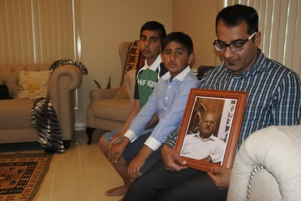 Kamran Ahmed, with sons Khakan and Sultan, holds a photo of his first cousin Sheikh Sajid Mehmood, who was killed in Pakistan on November 27. Photo: Stephen Jeffery