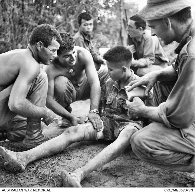 Three soldiers from the 3rd Battalion, The Royal Australian Regiment (3RAR), treat a captured North Vietnamese soldier. Photo: AWM