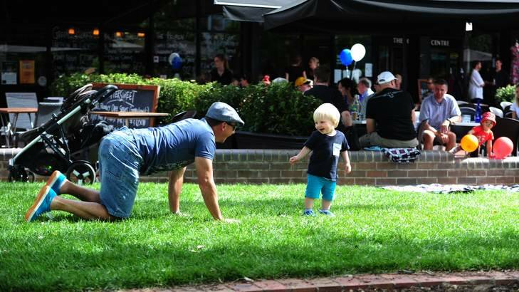 Michael Lyden of Bruce plays on the grass with his son Jacob, 18 months, at Green Square, Kingston. Photo: Melissa Adams