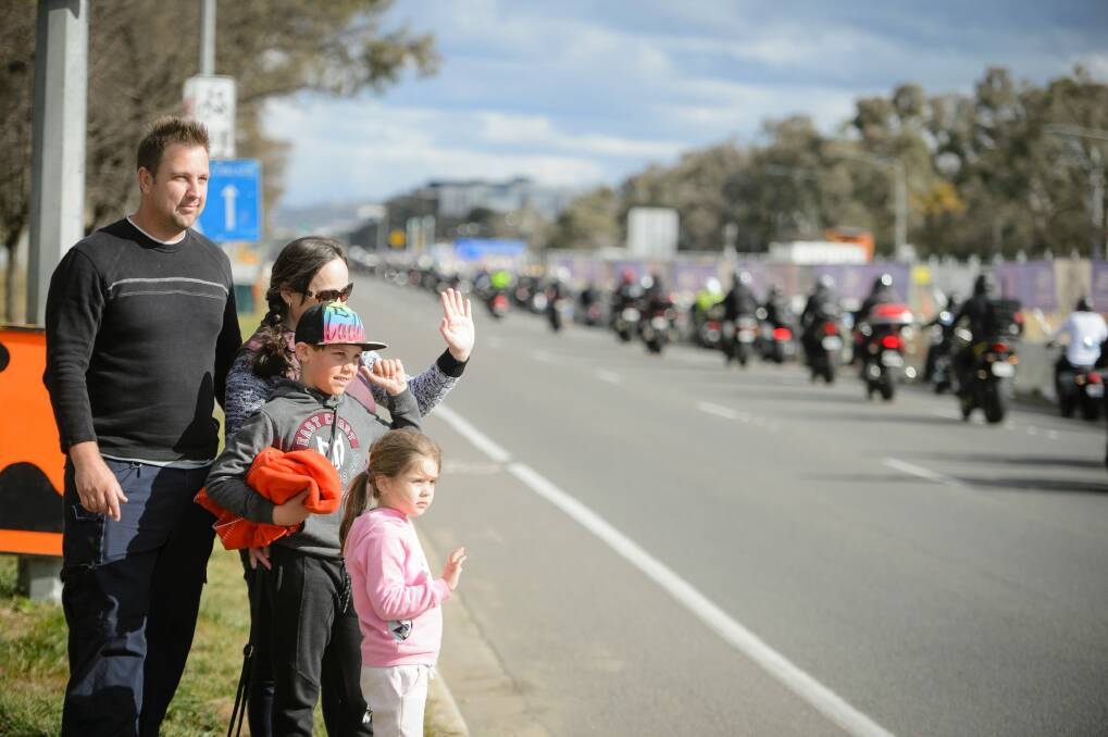 Shane Denaro, a police officer from Camden NSW, with his wife Shauna and children Lachlan, 10, and Indiana, 4, wave in support of the 2017 Ride for Remembrance as it makes its way down Northbourne Avenue.  Photo: Sitthixay Ditthavong