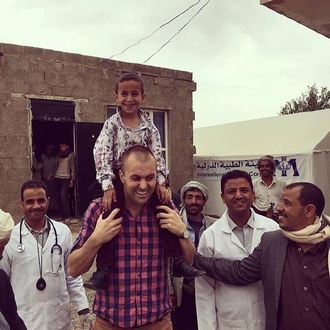 Simon Cowie, centre, with the child on his shoulders, in Yemen. Photo: Supplied