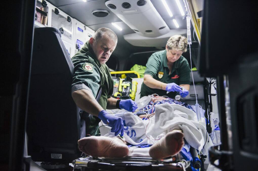 Steve Whan and Kath Csucsy treat a 79-year-old man in the back of an ambulance.   Photo: Rohan Thomson
