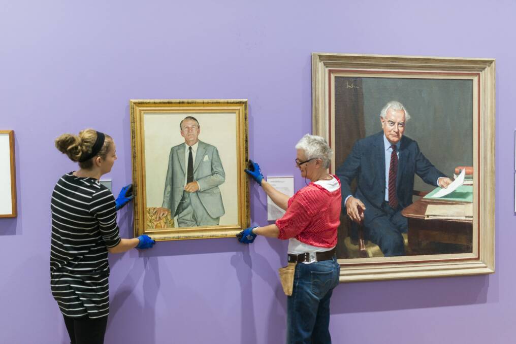 National Portrait Gallery staff hang a portrait of Malcolm Fraser next to a portrait of Gough Whitlam on Friday. Photo: Rohan Thomson