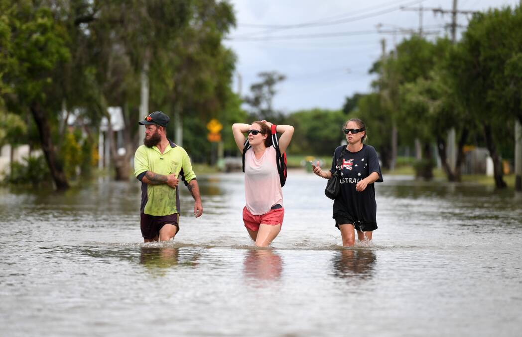 Local residents wade through flood water in the suburb of Hermit Park in Townsville Photo: AAP