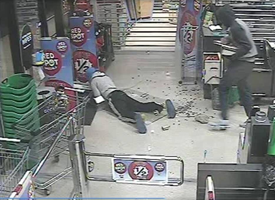 A screen grab from a CCTV video showing one of the men tripping and falling as he tries to flee with cash. Photo: Supplied by ACT Policing