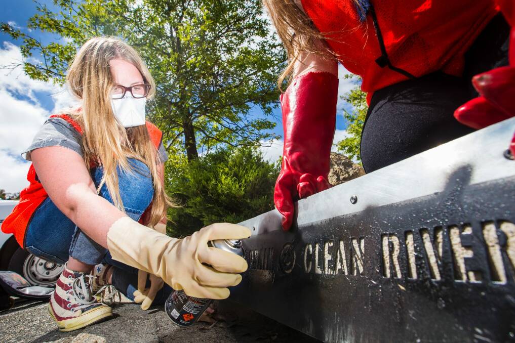 Year 11 student Hanna Gardiner, 16, stencils a message on a storm water drain to let the community know it runs into the Lake Ginninderra catchment wetlands. Photo: Matt Bedford