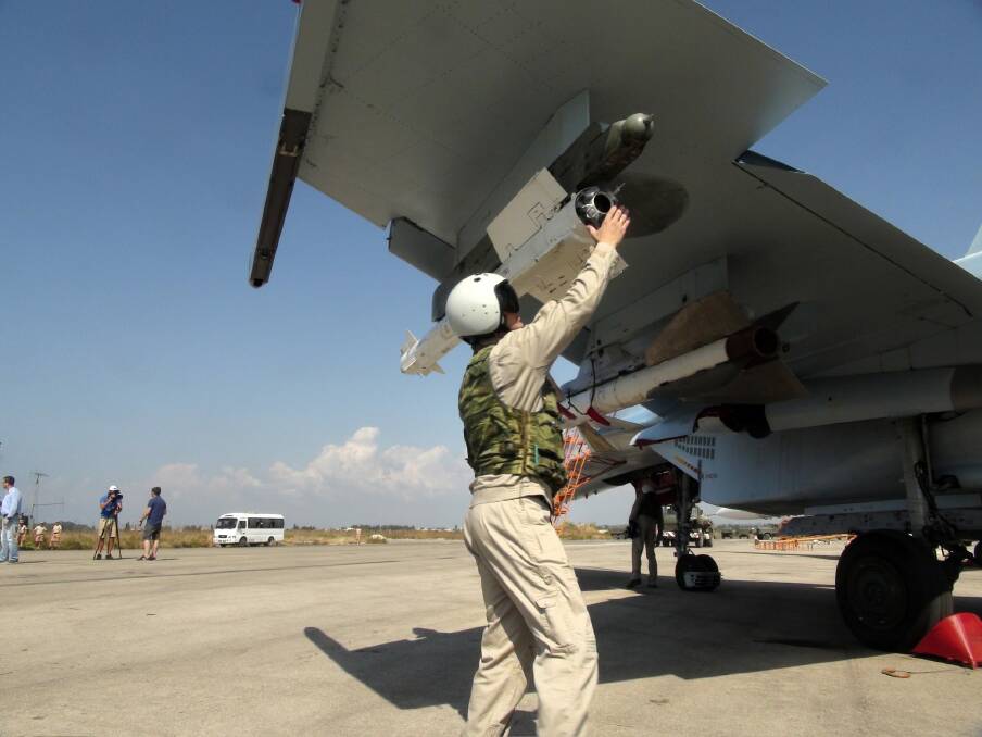In this photo taken on Monday, a Russian pilot fixes an air-to-air missile at his Su-30 jet fighter before a take off at Hmeimim airbase in Syria.  Photo: AP