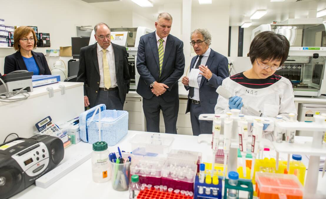 Minister for Medical and Health Research Meegan Fitzharris, with  provost of ANU Mike Calford, health director general Mike De 'Ath and ANU professor of medicine Mathew Cook at Canberra Clinical Genomics, while genomics technician Rong Liang works on far right.  Photo: Karleen Minney