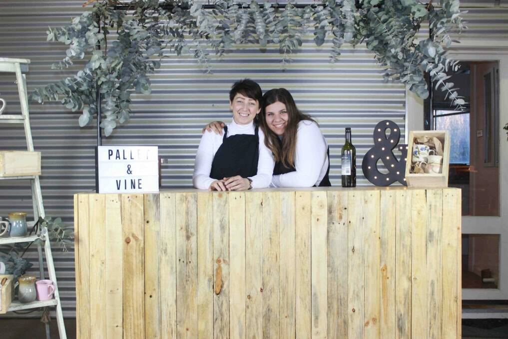Looking all cosy for winter, Anita Kirkowa and Gabrielle Petrevski of Pallet and Vine with their rustic bar made from the materials from boyandgirlco. Photo: Supplied