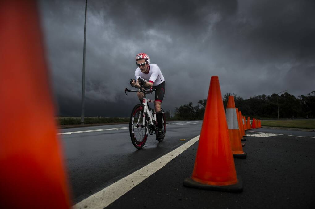 Threatening weather: A competitor takes part in the November Fest triathlon on Sunday as more dark clouds loom. Photo: Rohan Thomson