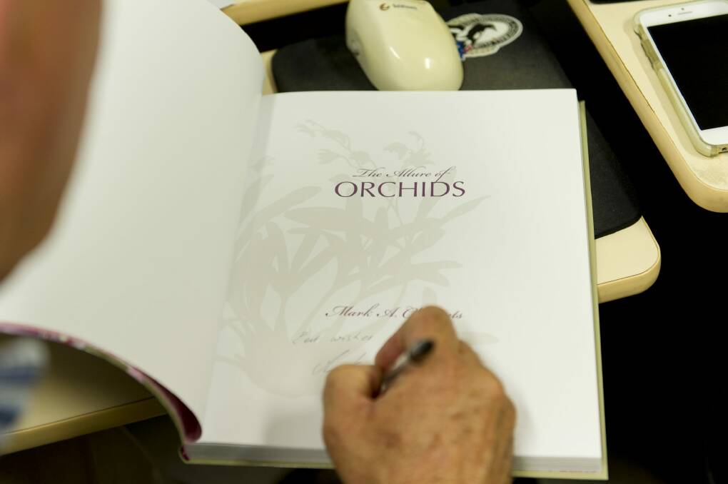 Dr Clements signs a copy of his book, The Allure of Orchids. Photo: Jay Cronan