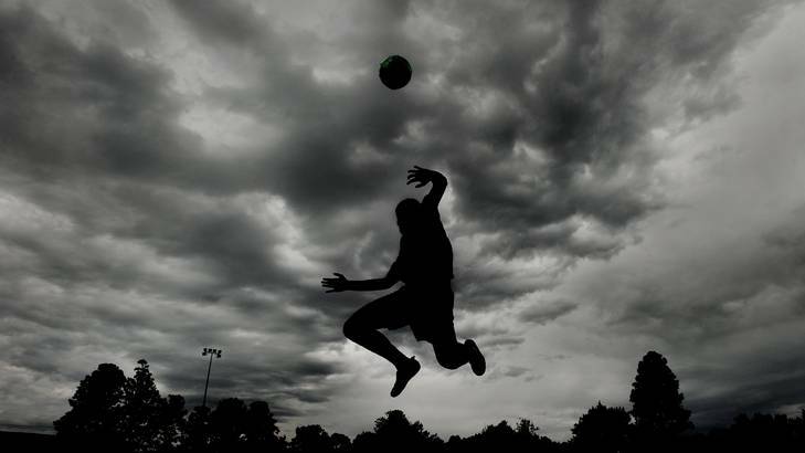 Jake Montgomery practising soccer as the dark clouds gather over Kingston Oval. Photo: Colleen Petch