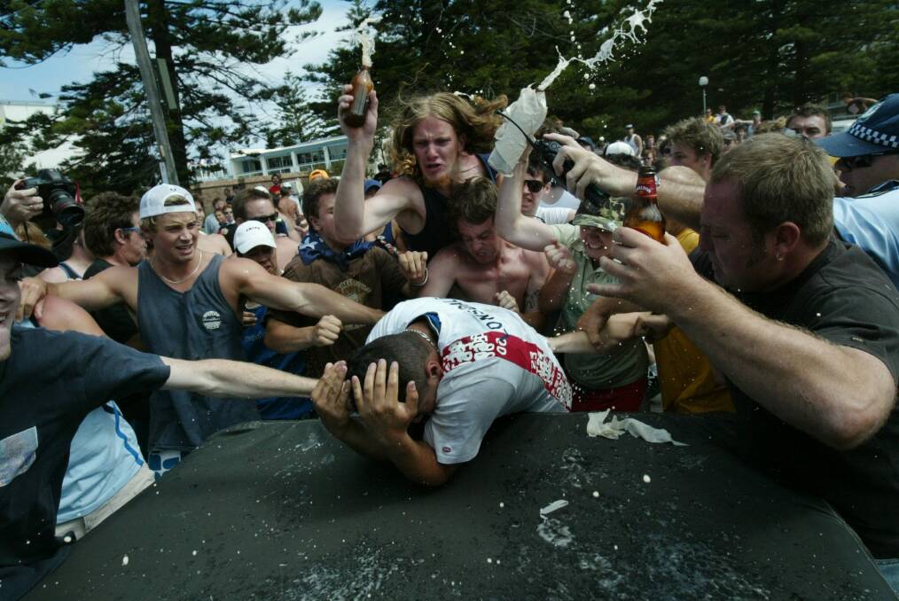 A mob surrounds and attacks a man of Middle Eastern appearance during the riots, pelting and bashing his head and body with bottles. Photo: Andrew Meares