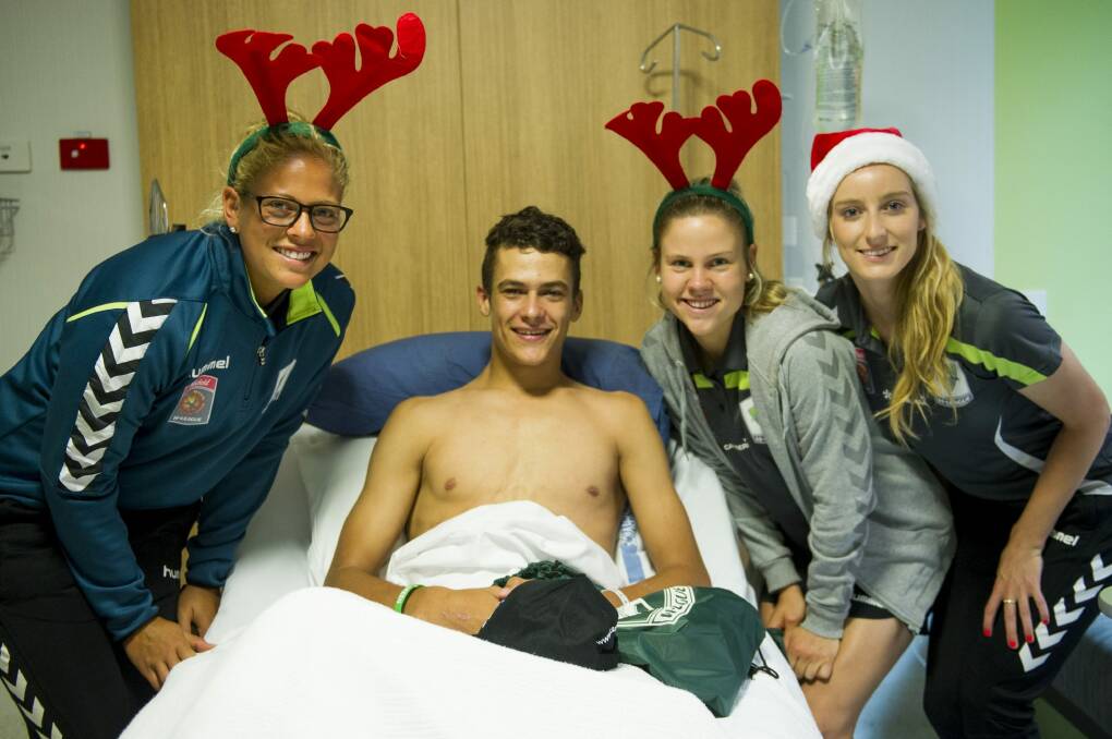 Canberra United players Chantel Jones, Sally Rojahn and Grace Field handed out Christmas gifts at Canberra Hospital on Thursday. They are pictured with patient Jeremy Bridger. Photo: Jay Cronan