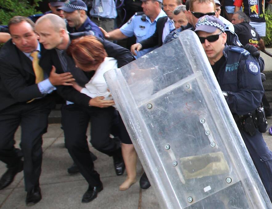 Former Prime Minister Julia Gillard is dragged away by her close protection team police to her car after hundreds of protesters from the Aboriginal Tent Embassy on Australia Day in 2012. Photo: Alex Ellinghausen