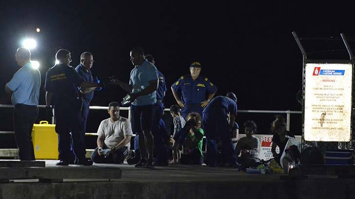 Customs officials and rescue personnel watch over survivors of the capsized boat at Christmas Island docks Photo: Sharon Tisdale