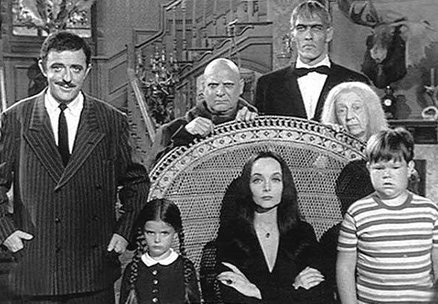 In <i>The Addams Family</i>(1964-1966). TV series. [L-R, behind the chair]: Uncle Fester (Jackie Coogan); Lurch (Ted Cassidy); Grandmama Addams (Blossom Rock). [L-R, front row]: Gomez Addams (John Astin); Wednesday (Lisa Loring); Morticia Addams (Carolyn Jones); Pugsley (Ken Weatherwax).  Photo: Internet