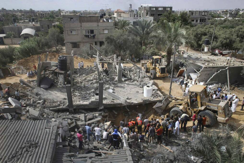 Palestinians gather as rescue workers search for victims under the rubble of a house which witnesses said was destroyed in an Israeli air strike in Khan Younis in the southern Gaza Strip on Thursday.
