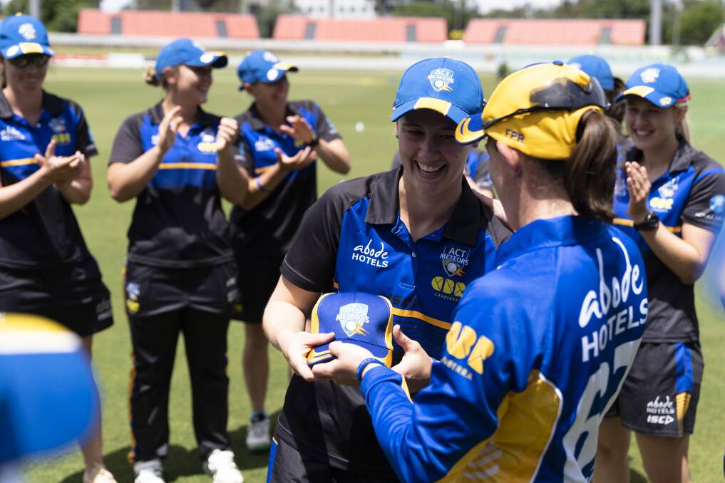 Anna Lanning is presented with her ACT Meteors cap by captain Erin Osborne. Photo: Lawrence Atkin