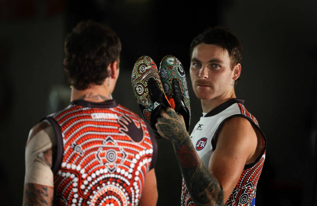 Man in the mirror: Nathan Wilson wearing the Indigenous jumper and with the special boots he will wear on Sunday against West Coast. Photo: Daniel Munoz