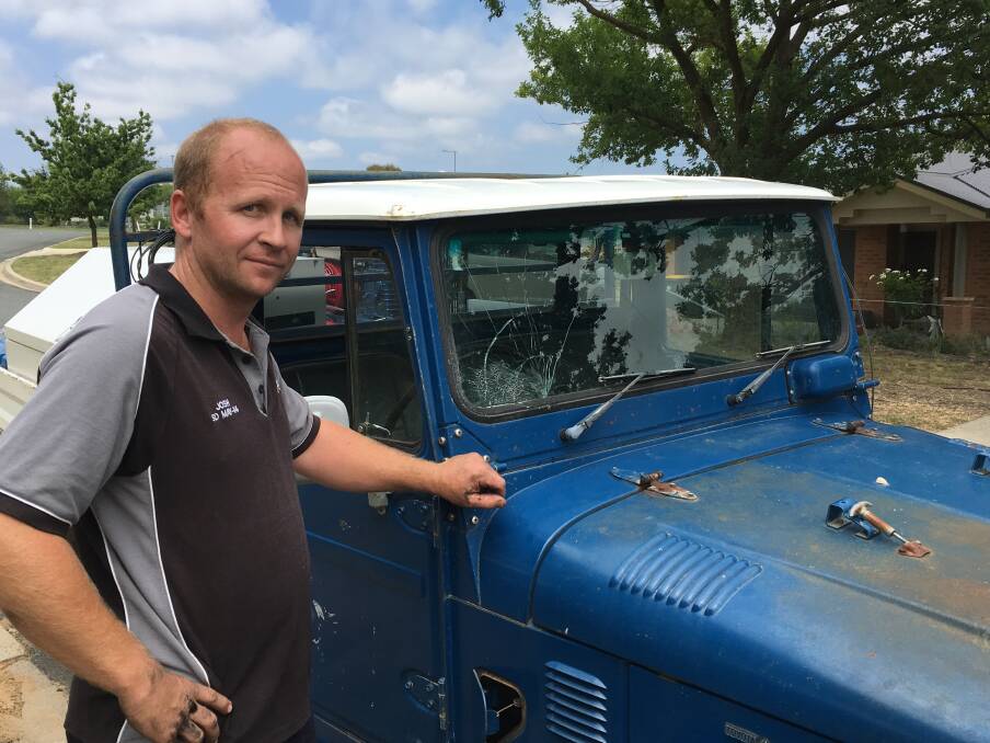 Josh Delaney, pictured, stands next to his four-wheel-drive that was struck by a potato fired from the Yarralumla side of Adelaide Avenue on Thursday morning. Photo: Jasper Lindell