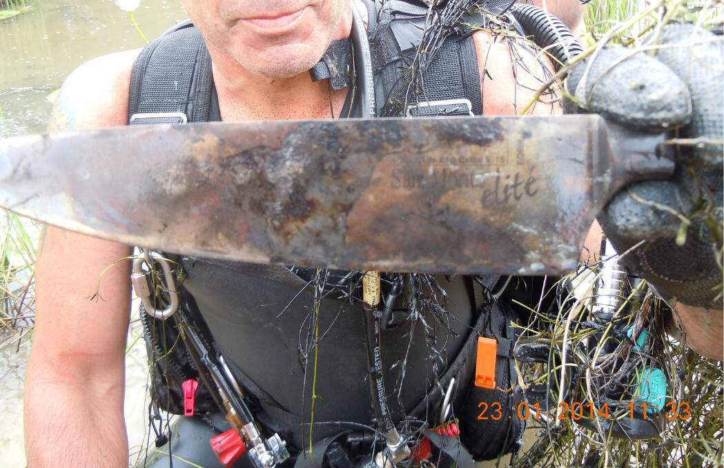 A police diver holds one of the knives recovered from the dam. Photo: ACT Policing